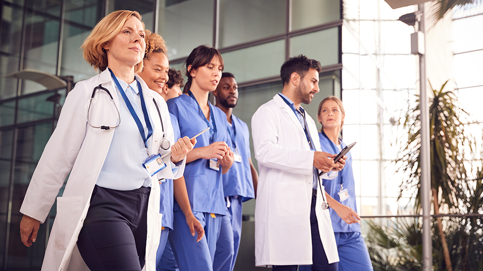 Gruppe von motivierten jungen Ärzten geht durch den Eingangsbereich eines Krankenhauses